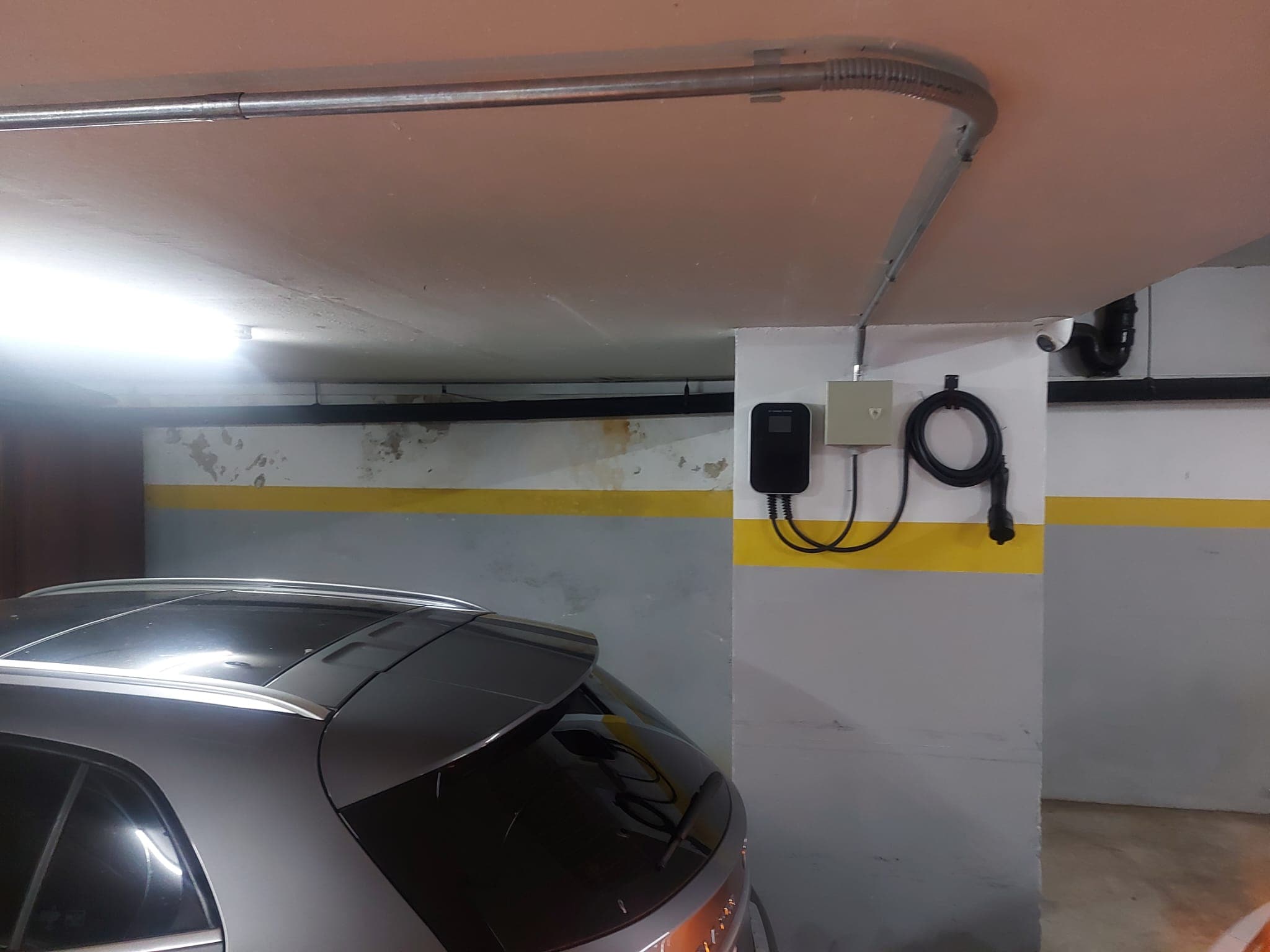 Rayforce wallbox installed on a column in a building garage, with its panel and the cable on its holder