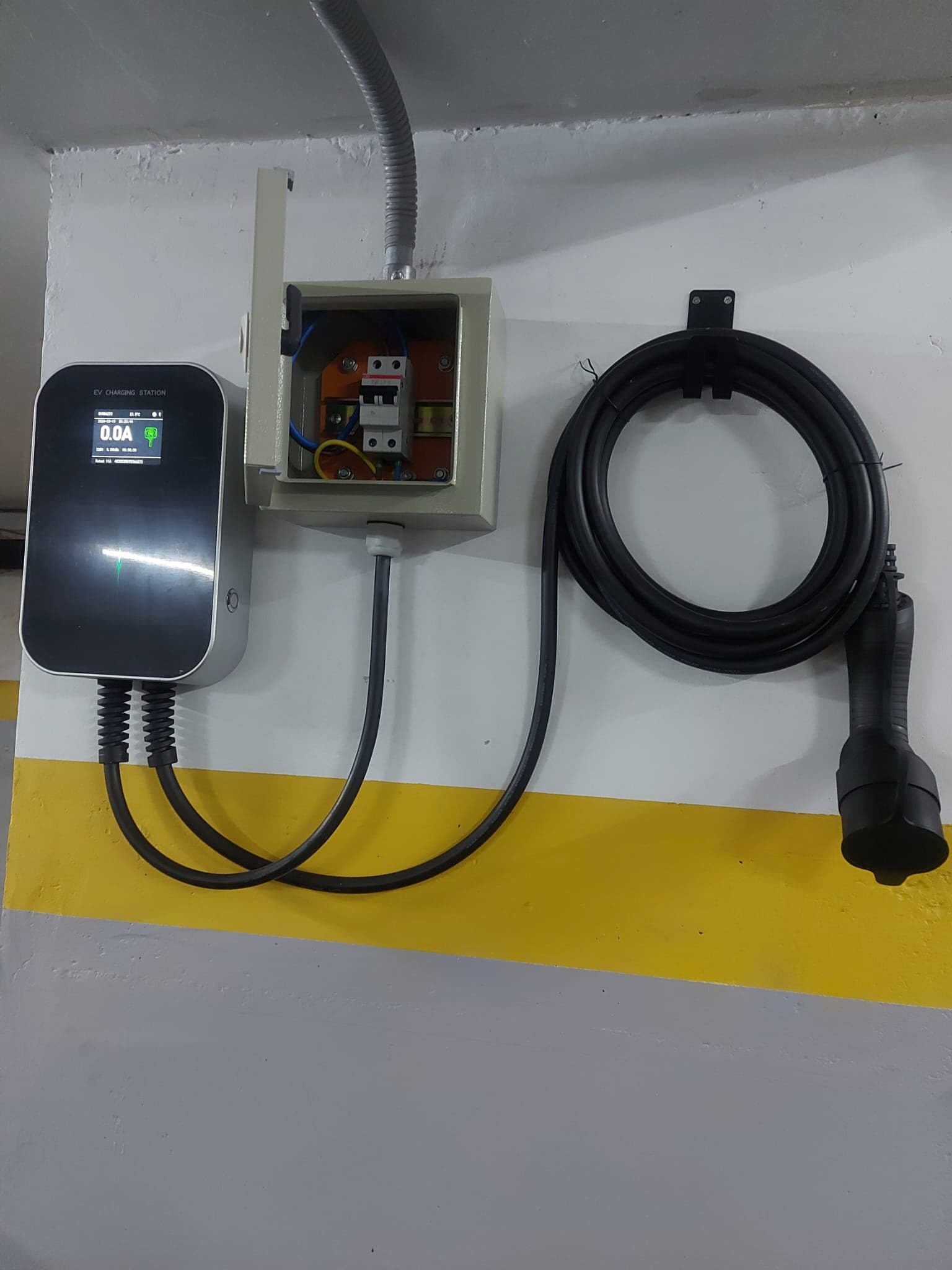 Wallbox with its protection panel open and the Type 2 cable hanging on its holder